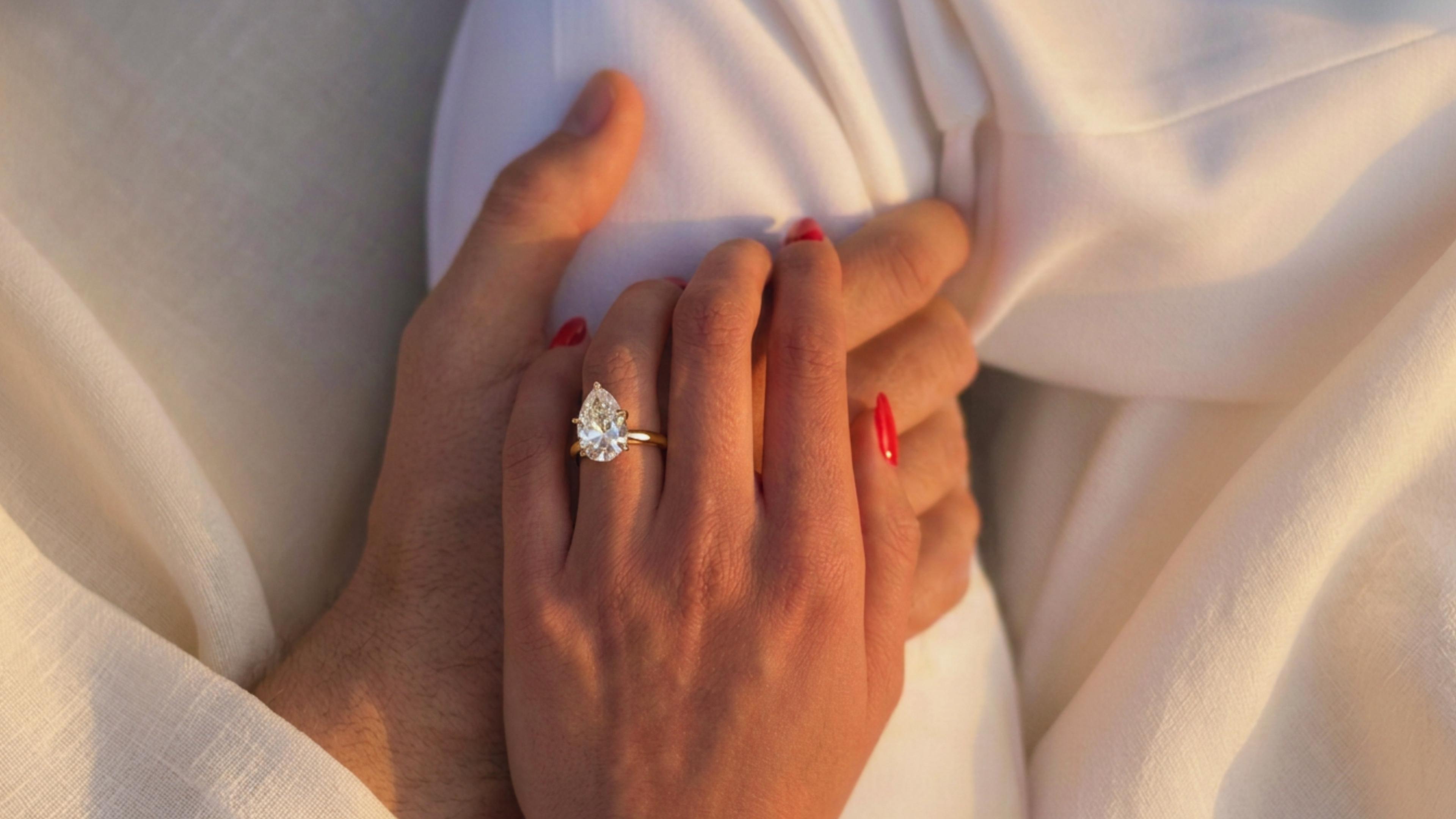 A couple's clasped hands, an engagement ring